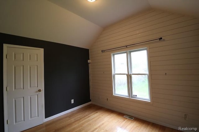 111 N Genesee St, Davison, MI 48423 - empty room with vaulted ceiling, light wood-style floors, wood walls, and baseboards