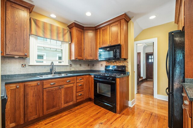 2323 Paris Ave SE, Grand Rapids, MI 49507 - kitchen featuring black appliances, a sink, light wood finished floors, brown cabinets, and dark countertops