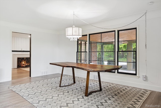 58540 Grand River Ave, New Hudson, MI 48165 - dining room with baseboards, wood finished floors, a warm lit fireplace, and a chandelier