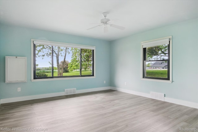 58540 Grand River Ave, New Hudson, MI 48165 - empty room featuring healthy amount of natural light, wood finished floors, a ceiling fan, and baseboards