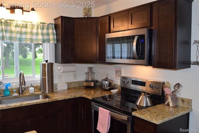 7448 Miller Rd, Swartz Creek, MI 48473 - kitchen featuring stainless steel appliances, a sink, dark brown cabinets, and light stone countertops