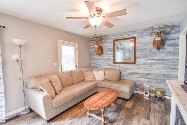493 Swan Ln, Coldwater, MI 49036 - living area with an accent wall, ceiling fan, wooden walls, wood finished floors, and baseboards