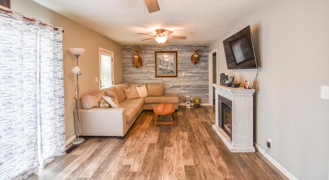 493 Swan Ln, Coldwater, MI 49036 - living area with ceiling fan, wood finished floors, baseboards, a glass covered fireplace, and wooden walls