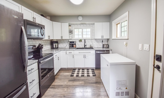 493 Swan Ln, Coldwater, MI 49036 - kitchen with stainless steel appliances, a sink, backsplash, wood finished floors, and white cabinets