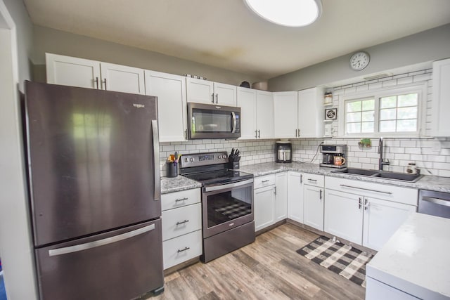 493 Swan Ln, Coldwater, MI 49036 - kitchen featuring stainless steel appliances, a sink, backsplash, white cabinetry, and light wood-style floors