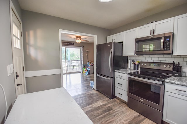 493 Swan Ln, Coldwater, MI 49036 - kitchen featuring stainless steel appliances, wood finished floors, white cabinetry, decorative backsplash, and a ceiling fan