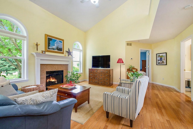 1432 Auston Ln, Chelsea, MI 48118 - living room featuring light wood-type flooring, ceiling fan, a warm lit fireplace, high vaulted ceiling, and baseboards