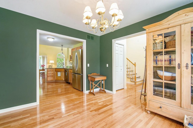1432 Auston Ln, Chelsea, MI 48118 - dining space featuring light wood finished floors, stairs, a chandelier, and baseboards