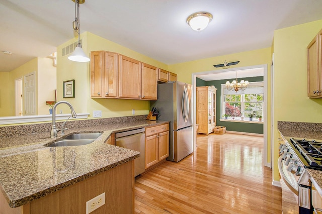 1432 Auston Ln, Chelsea, MI 48118 - kitchen with stainless steel appliances, a sink, a peninsula, light wood-style floors, and dark stone countertops