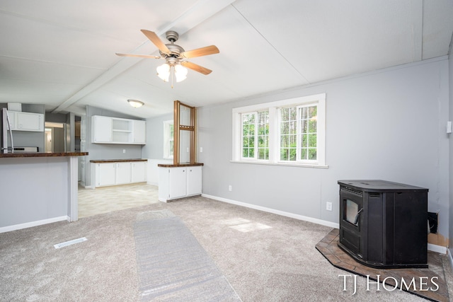 3010 E 96th St, Newaygo, MI 49337 - unfurnished living room featuring a wood stove, ceiling fan, light carpet, and baseboards