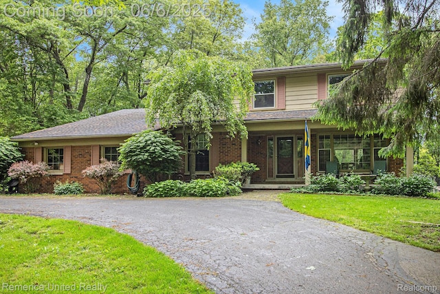 11187 Shadywood Dr, Brighton, MI 48114 - view of front of house featuring covered porch, driveway, a front lawn, and brick siding