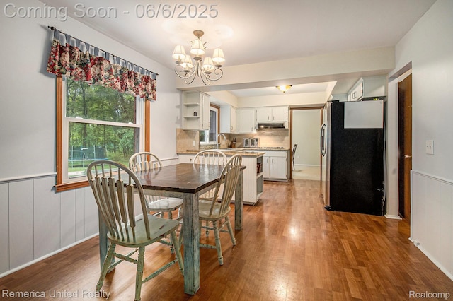 11187 Shadywood Dr, Brighton, MI 48114 - dining area with wood finished floors, a chandelier, and a wainscoted wall