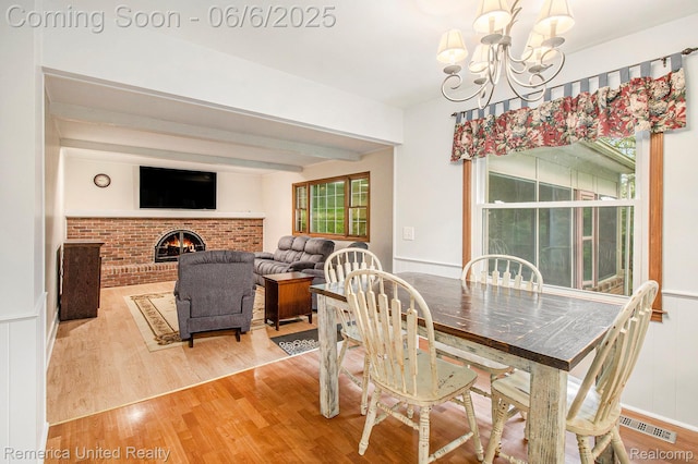 11187 Shadywood Dr, Brighton, MI 48114 - dining area with light wood-type flooring, a chandelier, beamed ceiling, and a fireplace