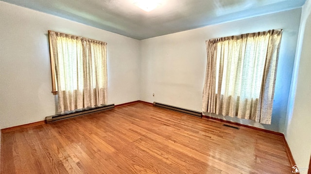 1220 N Raisinville Rd, Monroe, MI 48162 - empty room with a baseboard heating unit, plenty of natural light, and wood finished floors