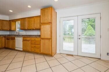 221 S Taylor St, New Buffalo, MI 49117 - kitchen featuring dishwasher, french doors, crown molding, brown cabinets, and dark countertops