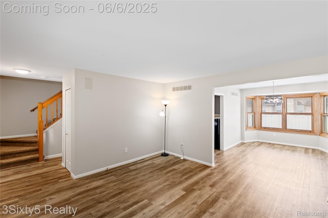 20605 Hickory St, Woodhaven, MI 48183 - spare room with wood finished floors, baseboards, stairs, and a chandelier