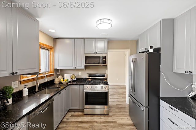 20605 Hickory St, Woodhaven, MI 48183 - kitchen with appliances with stainless steel finishes, a sink, light wood-type flooring, and dark stone counters