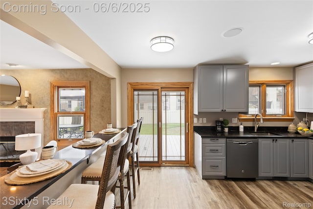 20605 Hickory St, Woodhaven, MI 48183 - kitchen featuring stainless steel dishwasher, gray cabinets, a sink, dark countertops, and light wood-style floors