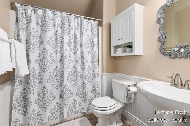 1020 E Woodlawn Ave, Hastings, MI 49058 - bathroom with a wainscoted wall, toilet, curtained shower, a sink, and tile patterned floors