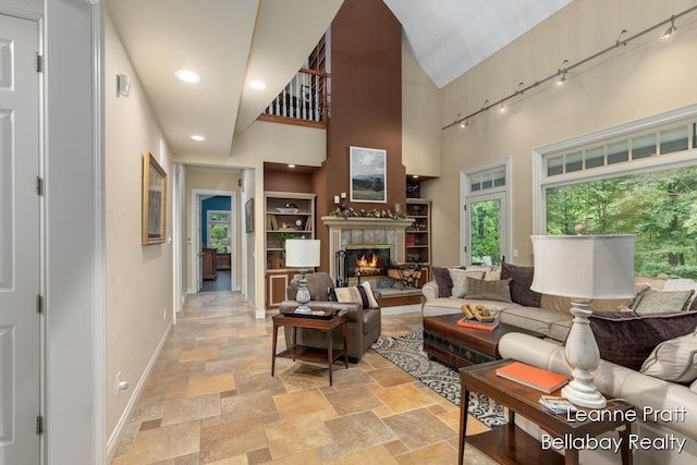 1020 E Woodlawn Ave, Hastings, MI 49058 - living area featuring baseboards, light stone finish floors, a premium fireplace, a high ceiling, and track lighting