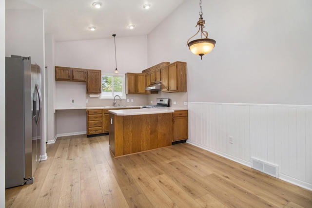 4273 20th St, Dorr, MI 49323 - kitchen with stainless steel appliances, under cabinet range hood, brown cabinetry, a peninsula, and wainscoting