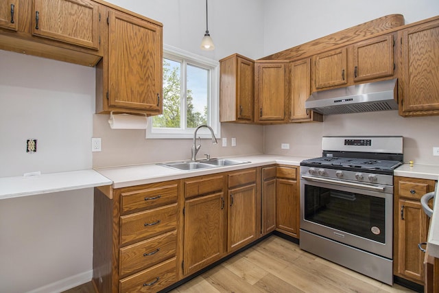 4273 20th St, Dorr, MI 49323 - kitchen with stainless steel gas stove, exhaust hood, a sink, light wood-style floors, and brown cabinetry
