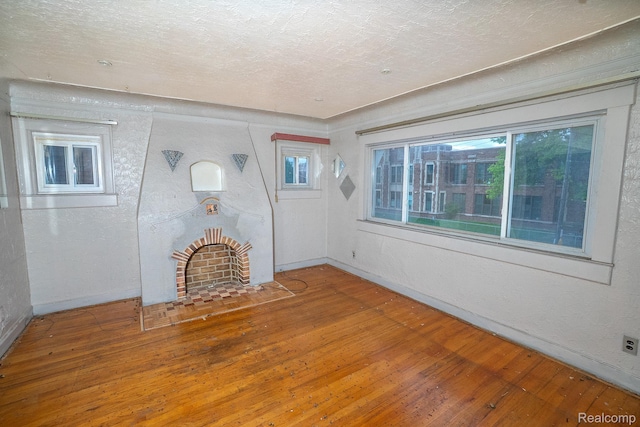 15859 Cloverlawn St, Detroit, MI 48238 - unfurnished living room featuring wood-type flooring, plenty of natural light, a fireplace with flush hearth, a textured ceiling, and a textured wall