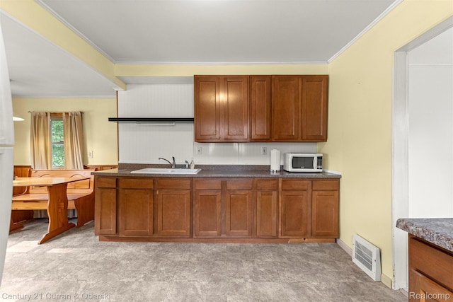 2143 Boldt St, Dearborn, MI 48124 - kitchen with white microwave, a sink, dark countertops, brown cabinets, and ornamental molding
