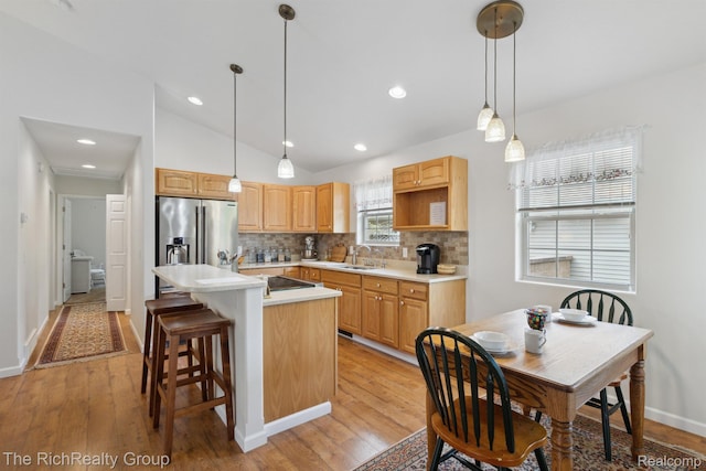 9798 Deer Track Ct, Interlochen, MI 49643 - kitchen featuring stainless steel fridge with ice dispenser, a sink, tasteful backsplash, a center island, and light wood finished floors