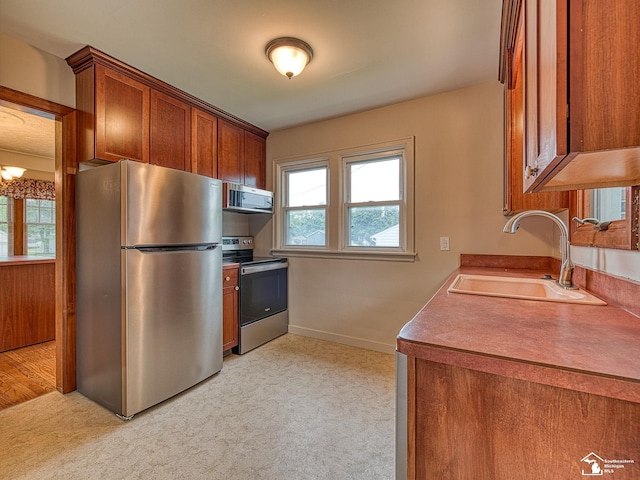27145 James Ave, Flat Rock, MI 48134 - kitchen featuring stainless steel appliances, a sink, light carpet, brown cabinetry, and baseboards
