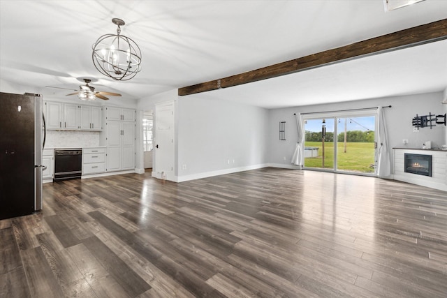 303 E Xy Ave, Vicksburg, MI 49097 - unfurnished living room with a glass covered fireplace, ceiling fan, a chandelier, dark wood-style floors, and beam ceiling