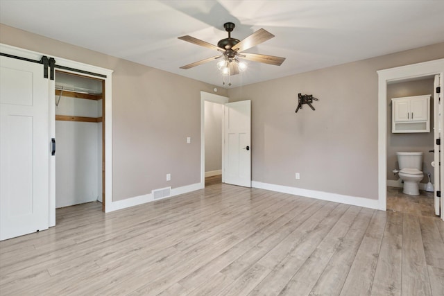 303 E Xy Ave, Vicksburg, MI 49097 - unfurnished bedroom with light wood-style flooring, baseboards, and a barn door