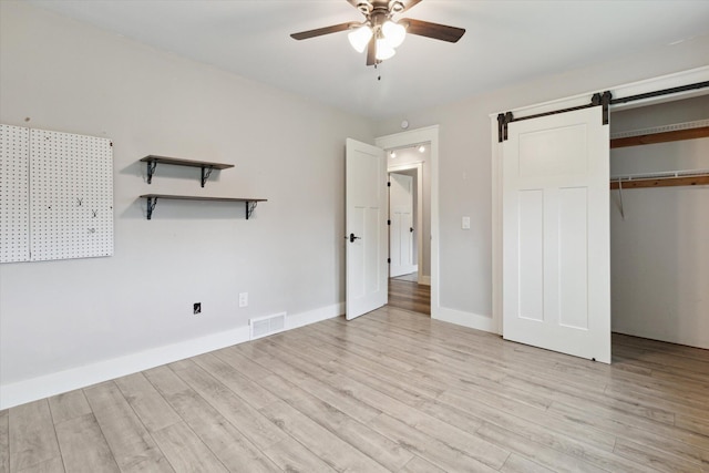 303 E Xy Ave, Vicksburg, MI 49097 - unfurnished bedroom featuring light wood-type flooring, a closet, baseboards, and a barn door