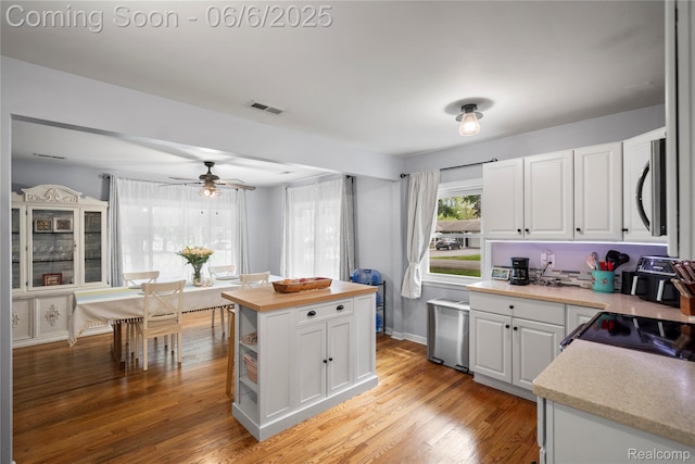 6226 Rowley Blvd, Waterford, MI 48329 - kitchen with white cabinets, stainless steel microwave, wooden counters, light wood-style flooring, and ceiling fan