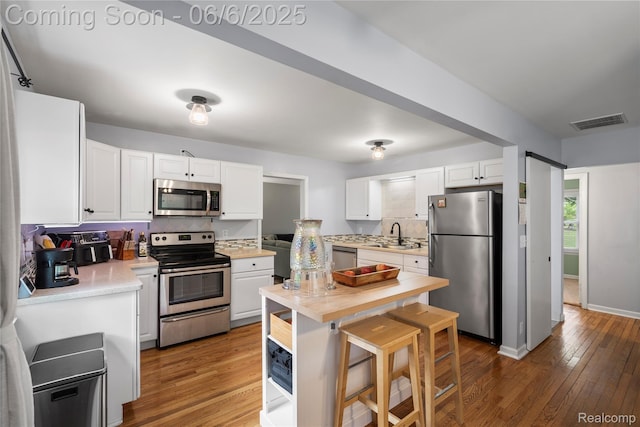 6226 Rowley Blvd, Waterford, MI 48329 - kitchen with stainless steel appliances, light countertops, hardwood / wood-style flooring, white cabinets, and a sink