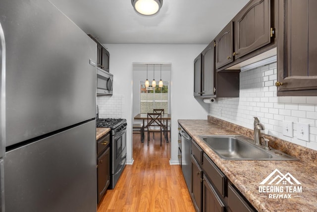 2203 Porter St SW Unit 104, Wyoming, MI 49519 - kitchen with stainless steel appliances, a sink, light wood-style flooring, backsplash, and pendant lighting