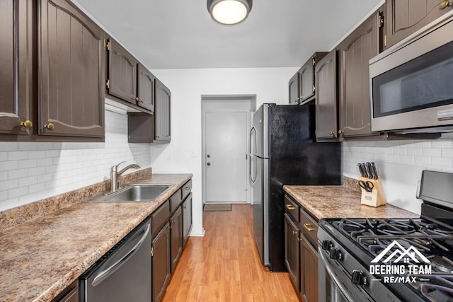 2203 Porter St SW Unit 104, Wyoming, MI 49519 - kitchen with appliances with stainless steel finishes, a sink, light wood-type flooring, decorative backsplash, and light countertops