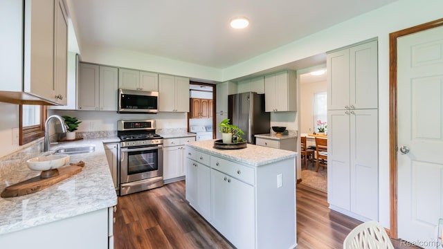 1755 Country View Dr, Okemos, MI 48864 - kitchen featuring stainless steel appliances, a sink, a kitchen island, dark wood-style flooring, and washer and dryer