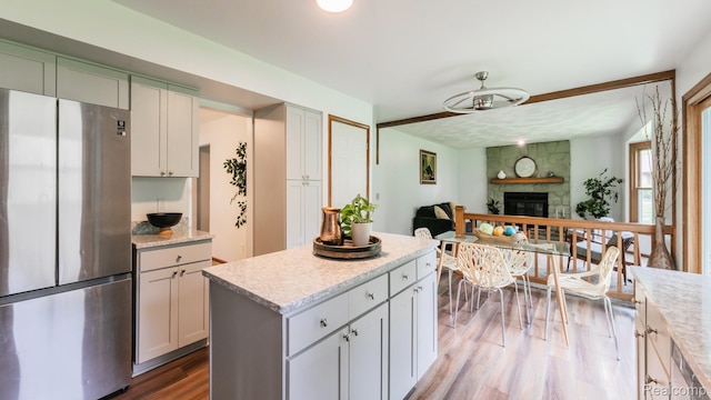 1755 Country View Dr, Okemos, MI 48864 - kitchen featuring freestanding refrigerator, wood finished floors, a fireplace, open floor plan, and ceiling fan
