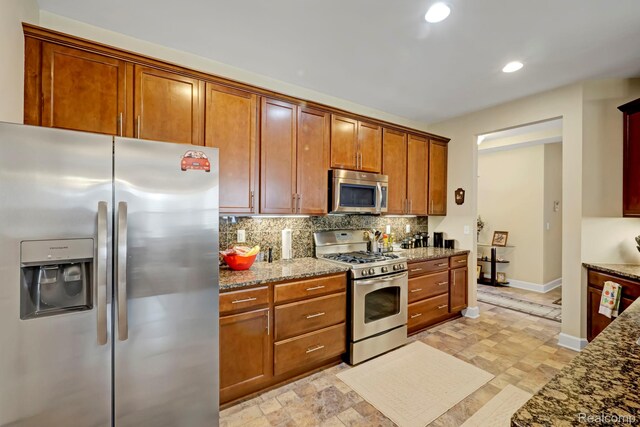 59649 Mallory Ln, South Lyon, MI 48178 - kitchen with appliances with stainless steel finishes, tasteful backsplash, dark stone countertops, light stone finish flooring, and recessed lighting