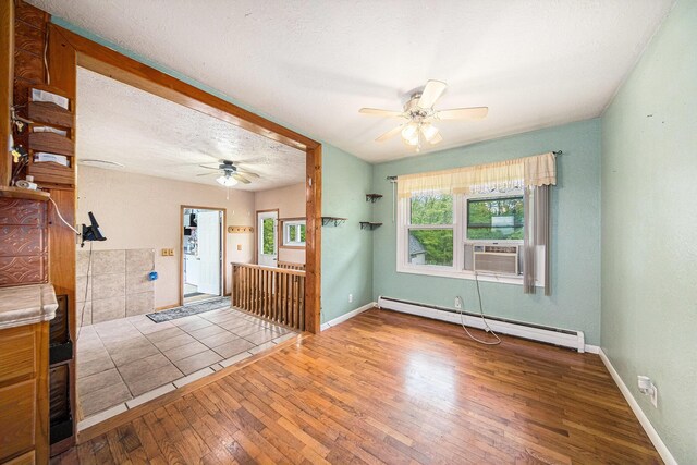 3225 Fishville Rd, Grass Lake, MI 49240 - unfurnished living room with a baseboard radiator, ceiling fan, hardwood / wood-style floors, cooling unit, and baseboards