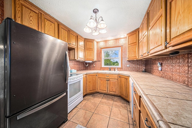 3225 Fishville Rd, Grass Lake, MI 49240 - kitchen featuring freestanding refrigerator, white electric stove, tile counters, a sink, and backsplash