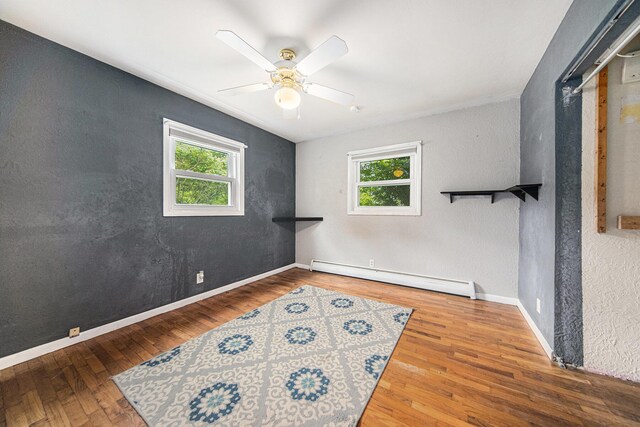 3225 Fishville Rd, Grass Lake, MI 49240 - spare room featuring baseboard heating, plenty of natural light, a ceiling fan, wood finished floors, and a textured wall