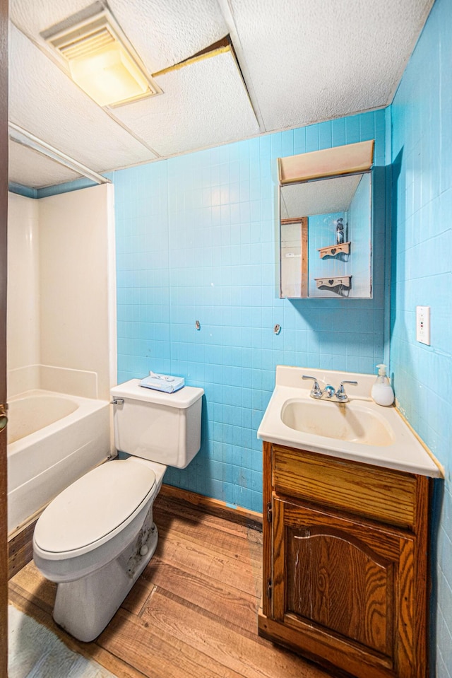 3225 Fishville Rd, Grass Lake, MI 49240 - bathroom with wood finished floors, toilet, vanity, a textured ceiling, and tile walls