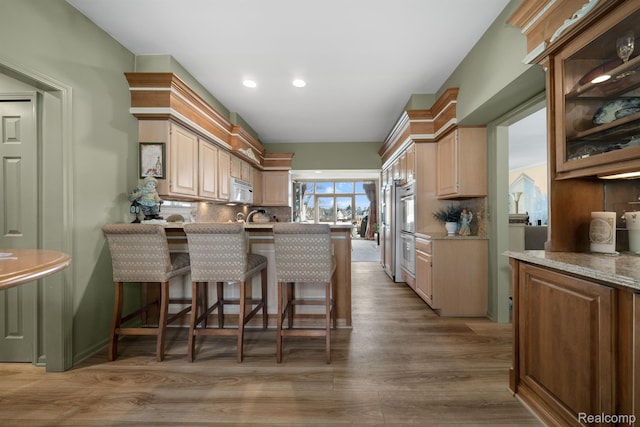 536 Cambridge Way, Bloomfield Hills, MI 48304 - kitchen with white microwave, tasteful backsplash, a peninsula, light wood finished floors, and stainless steel double oven