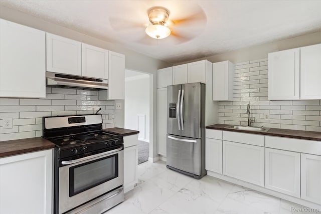 14134 Syracuse St, Southgate, MI 48180 - kitchen with under cabinet range hood, butcher block counters, appliances with stainless steel finishes, a sink, and light marble finish floors