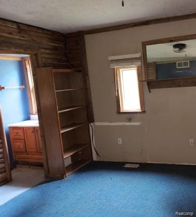 1747 Tennis Ct, Pleasant Lake, MI 49272 - unfurnished bedroom featuring light carpet, log walls, and a textured ceiling