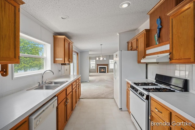 17055 Blackfoot Trl, Howard City, MI 49329 - kitchen with white appliances, a sink, under cabinet range hood, a textured ceiling, and brown cabinetry