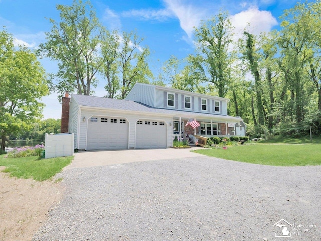 11963 Egan Hwy, Brooklyn, MI 49230 - view of front facade with gravel driveway, covered porch, a garage, a front yard, and a chimney