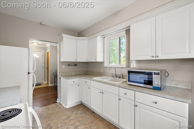 15501 Portis St, Northville, MI 48170 - kitchen featuring stainless steel microwave, freestanding refrigerator, a sink, white cabinets, and light countertops
